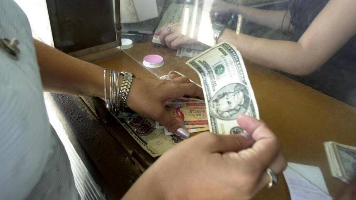Una cajera cambia dólares por pesos cubanos en La Habana. Las remesas de los cubanos que viven en Estados Unidos se han convertido en el salvavidas de muchos en la isla.