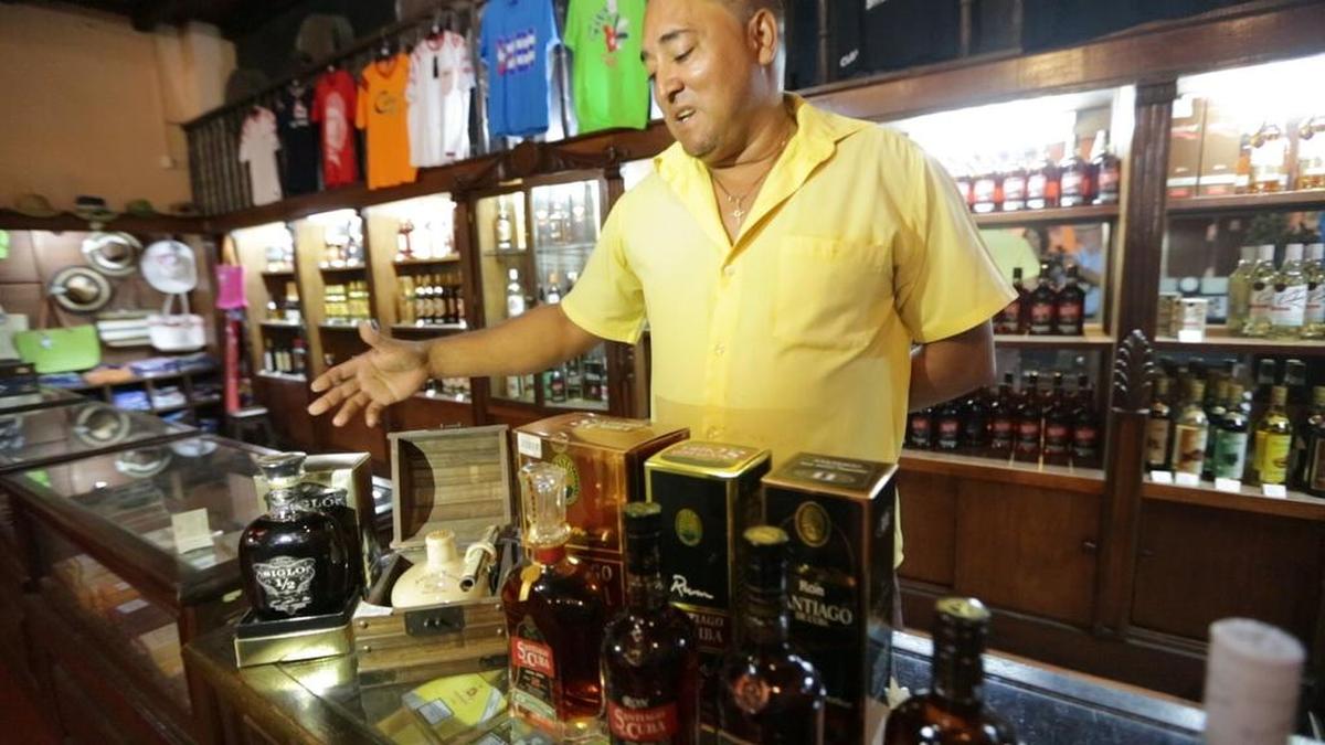 Marvin Peña, cantinero de La Barrita del Ron Caney en Santiago de Cuba, junto a la antigua fábrica Bacardí, muestra diferentes tipos de ron. El Ron Caney, que se destila en esa fábrica, está entre las marcas en la lista de prohibiciones del Departamento de Estado.