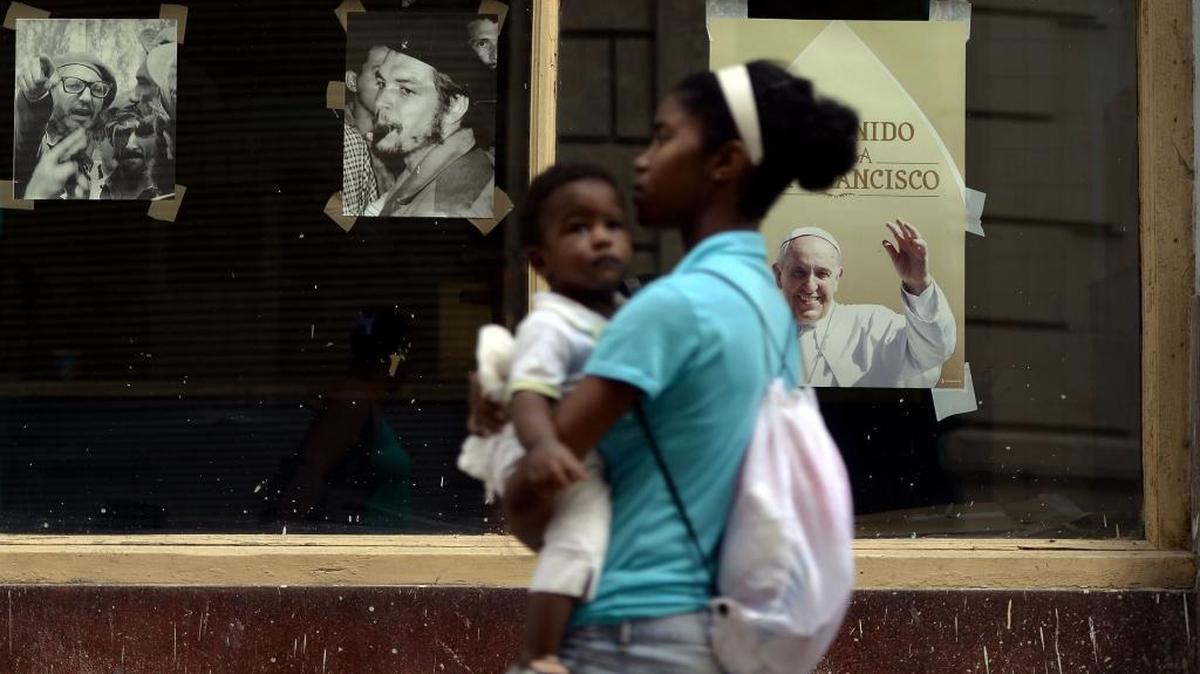 
Una madre con su hijo pasan una ventana con las imágenes del Che Guevara y el papa Francisco, el viernes 18 de septiembre en La Habana.
