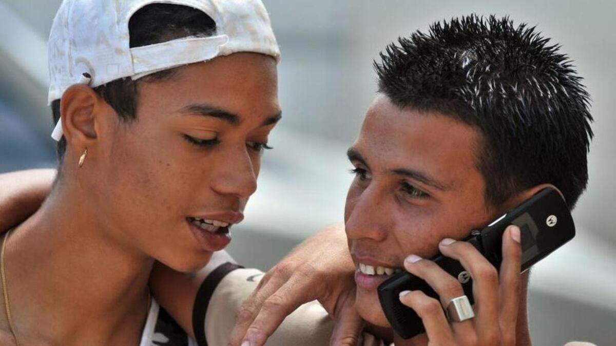 Dos jóvenes conversan por teléfono en La Habana, Cuba.
