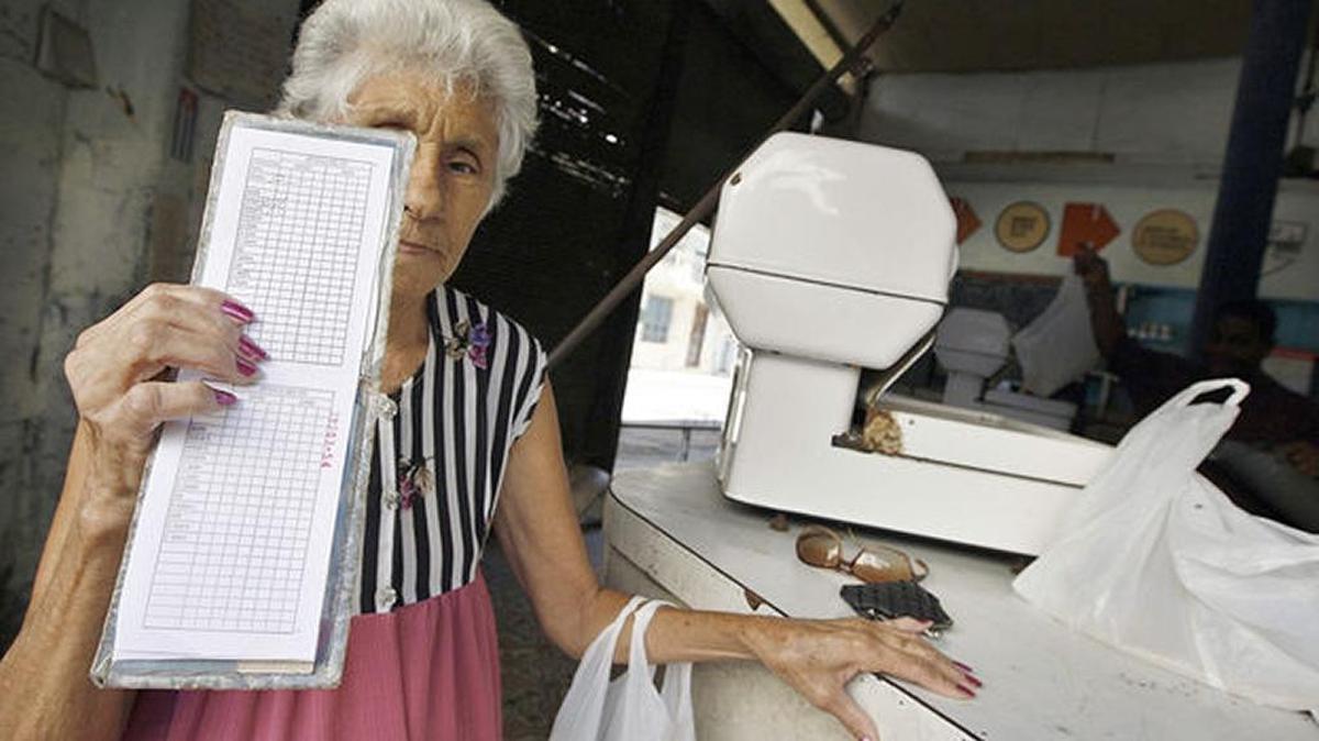 Una anciana muestra la libreta de racionamiento de productos básicos en Cuba.