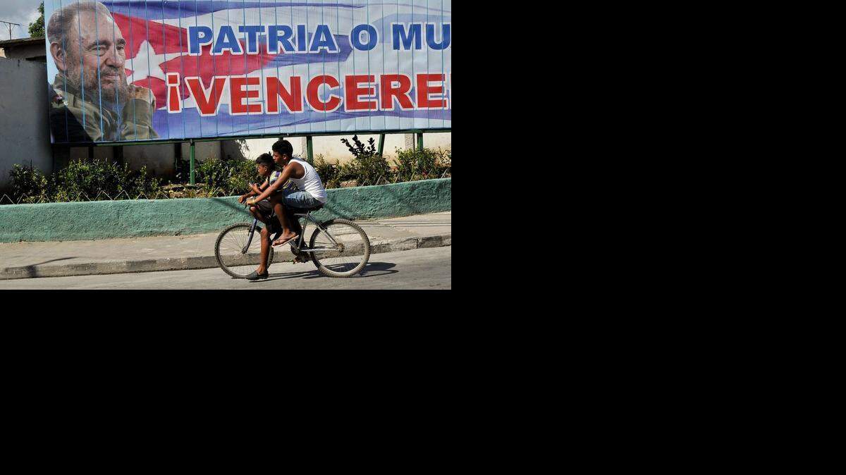
Dos jóvenes cubanos pasan en bicicleta frente a una valla con la imagen del ex gobernante Fidel Castro, en La Habana, el 12 de agosto.
