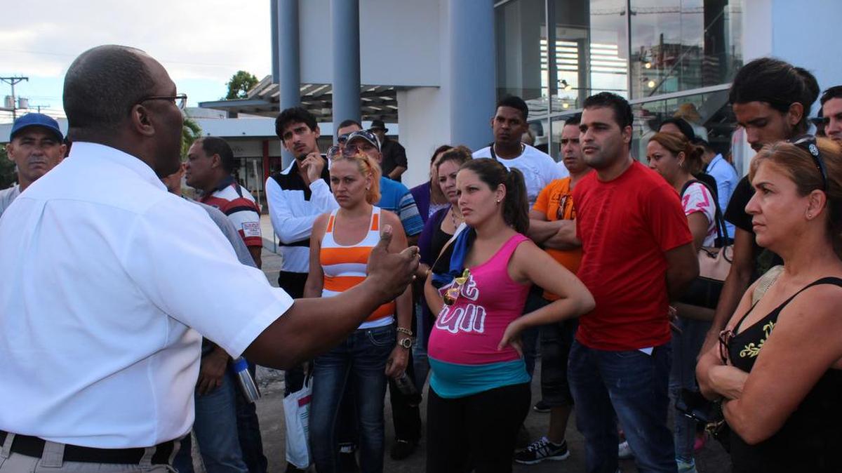 Un funcionario panameño (i) explica a los cubanos varados en Paso Canoas (Panamá), el miércoles 10 de febrero de 2016, el procedimiento que les permite comprar el boleto de avión, por 523,50 dólares cada uno, para viajar a México.