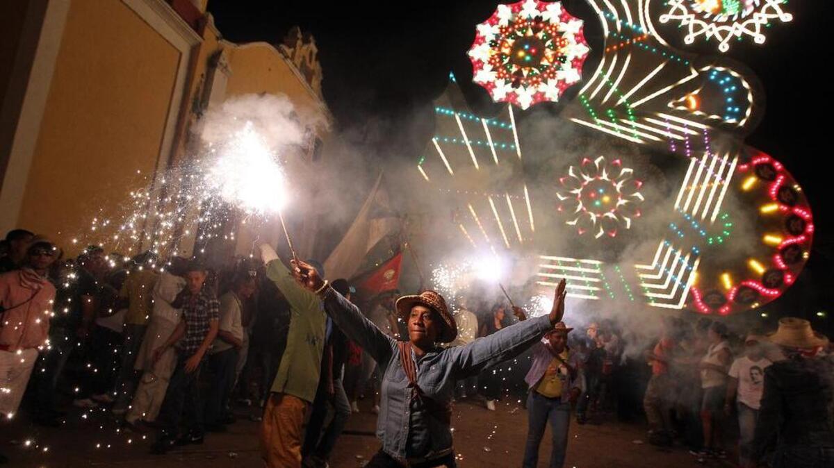 Una mujer baila mientras decenas de personas lanzan cohetes, y fuegos de artificio, en la madrugada del 25 de diciembre de 2013, en la Central provincia de Villa Clara en el poblado de San Juan de los Remedios (Cuba), durante las tradicionales Parrandas de Remedios, la festividad más antigua de Cuba.