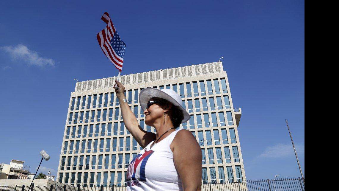 Una mujer ondea una bandera frente a la embajada de Estados Unidos en la Habana, Cuba el lunes 20 de julio.