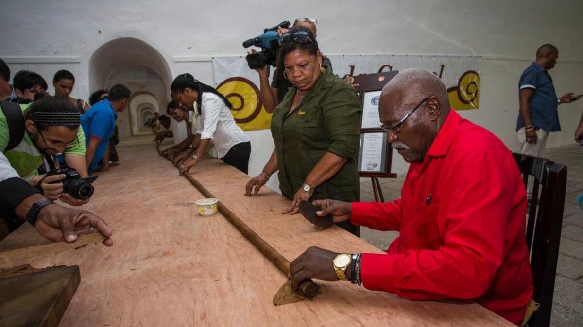 El tabaquero José “Cueto” Castelar tuerce junto con ayudantes el tabaco más largo del mundo, en La Habana.