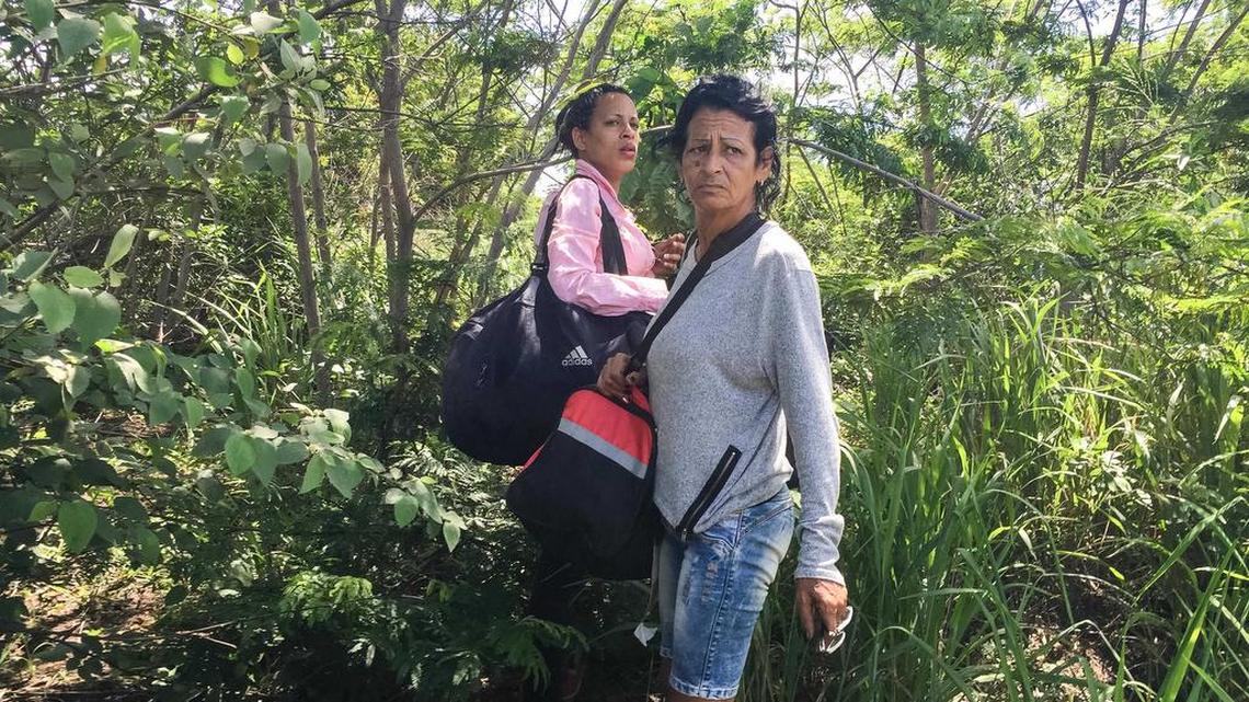 Liset Barrios y Marta Amaro esperan ansiosas por una señal para ir a buscar los autos que las llevarán a alguna parte después de haber cruzado a Brasil.