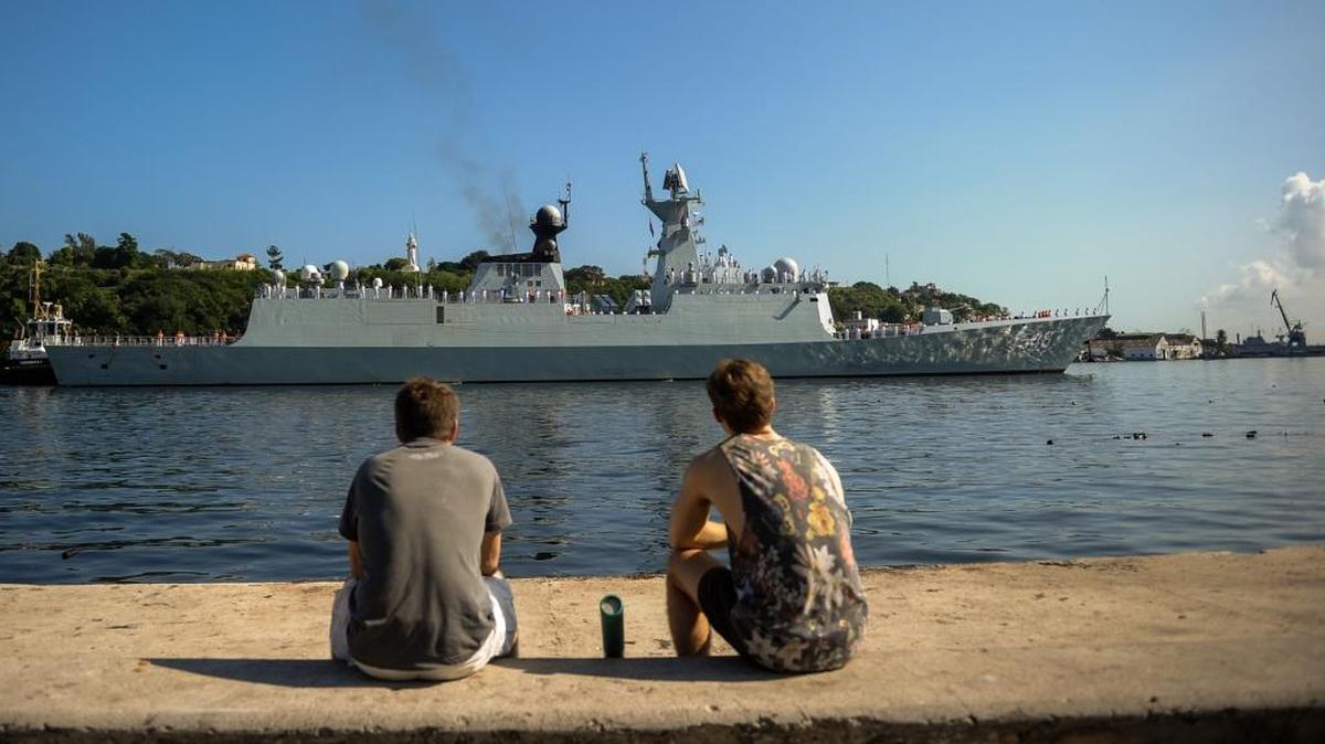 Dos hombres en el Malecón de La Habana observan un buque de la Armada China a su entrada al puerto capitalino.