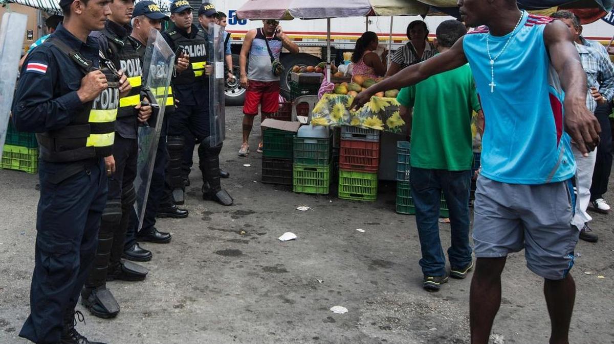 Un migrante cubano protesta frente a una línea de policías. Tanto las autoridades panameñas como las de Costa Rica incrementaron la presencia policial y del ejército tras los incidentes del miércoles en la frontera de ambos países, cuando más de 1,000 cubanos entraron por la fuerza a territorio costarricense. Horas después fueron devueltos a Panamá.