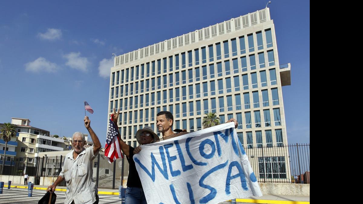 
Un grupo de personas sostiene una pancarta y agita banderas el lunes 20 de julio frente a la embajada de Estados Unidos en La Habana .



