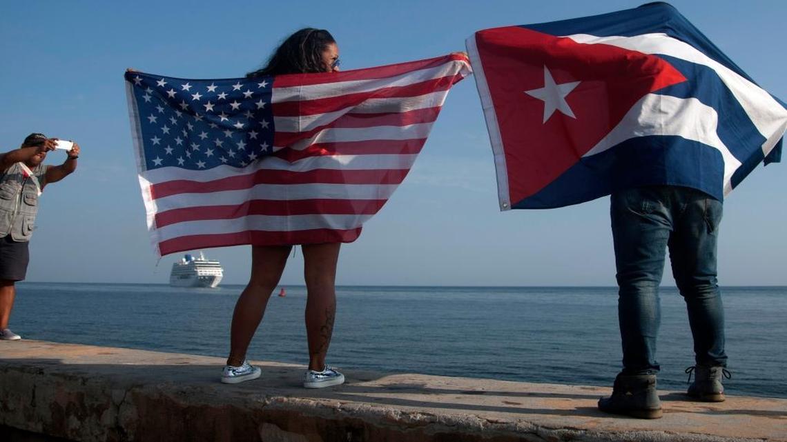 Yaney Cajigal (izq) y Dalwin Valdés con banderas de Estados Unidos y Cuba esperan en La Habana la llegada del primer crucero de Estados Unidos el 2 de mayo del 2016.