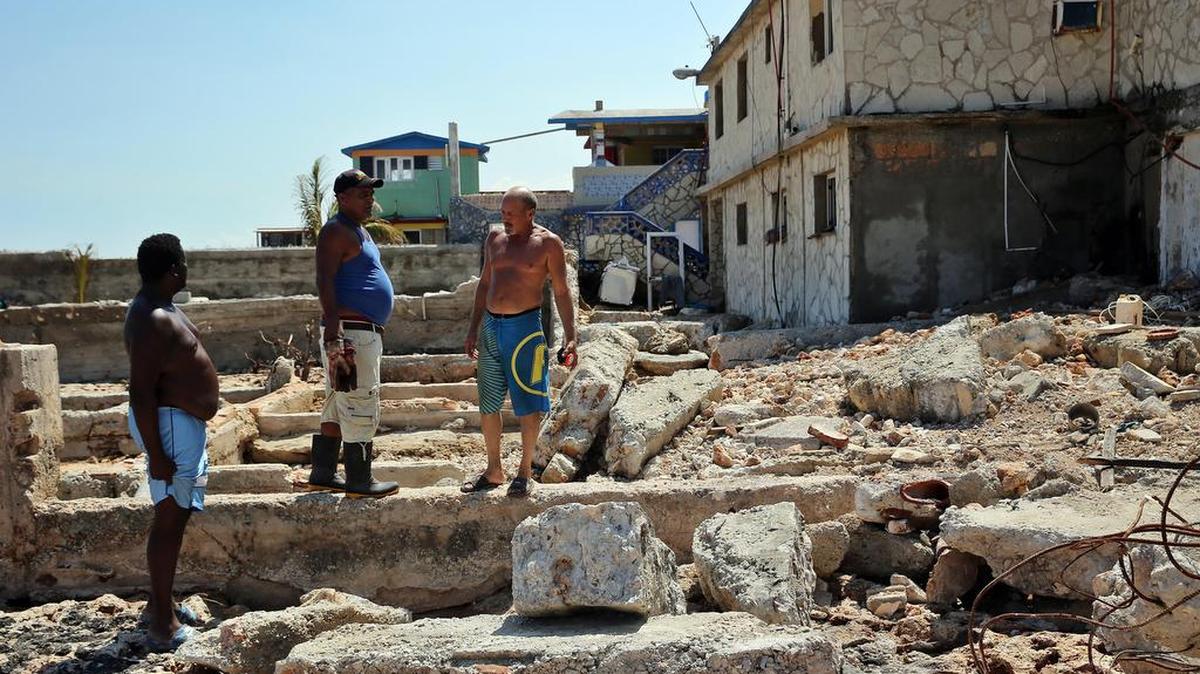 Tres hombres observan los destrozos ocasionados a sus casas el viernes 15 de septiembre, en el poblado de Cojímar, en La Habana (Cuba), casi una semana después del paso del huracán Irma.