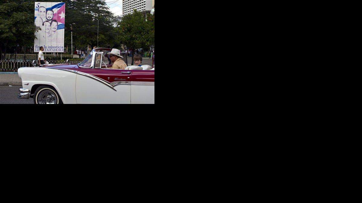 Un turista pasa frente a un cartel que muestra los retratos de “Los Cinco” en La Habana, Cuba, el miércoles 17 de diciembre de 2014.