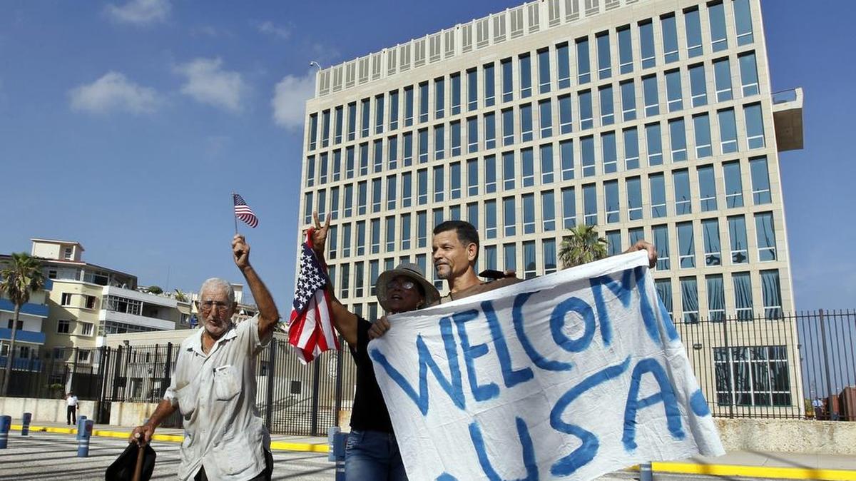 
Un grupo de personas sostiene una pancarta y agita banderas en julio, frente a la embajada de Estados Unidos en La Habana. 
