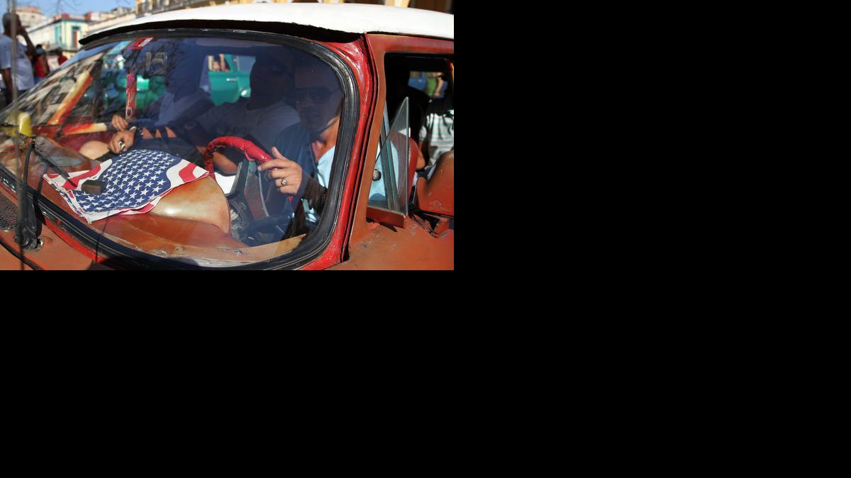 
Un hombre maneja su taxi con una bandera de Estados Unidos el miércoles en una calle de La Habana. 
 