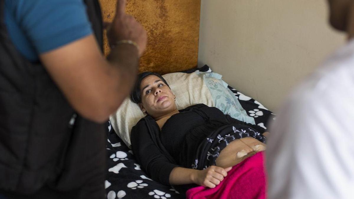 
Diez días después de una cesárea, los puntos en la herida de Sheylan Cárdenas aún supuran, pero no puede acudir a un hospital para tratarse. El enfermero Discel Rodríguez, a la izquierda, y su esposo Jorge Yanes la atienden.


