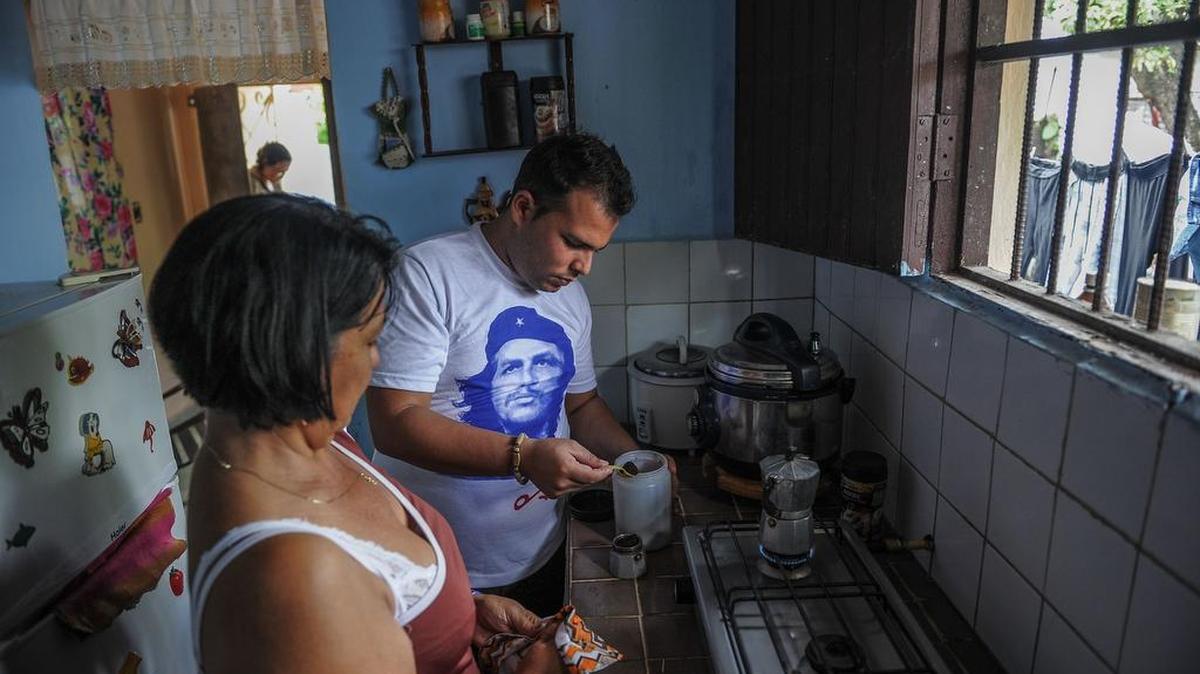 Daniel Ernesto, uno de los llamados "Ernesticos", en honor al guerrillero argentino-cubano Ernesto "Che" Guevara- ayuda a su madre Carmen Ruiz en la cocina de su casa en Santa Clara, provincia de Villa Clara, en septiembre 29 de 2017.