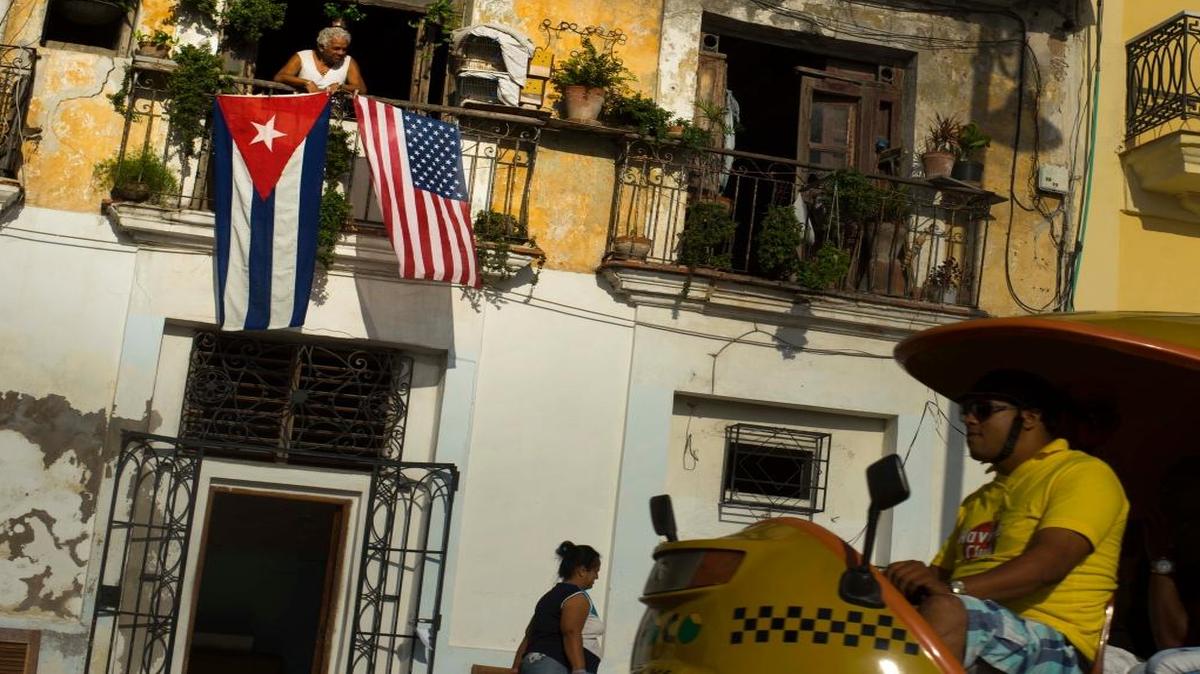 Un residente de La Habana Vieja coloca banderas de Cuba y EEUU en el balcón de su vetusta vivienda.
