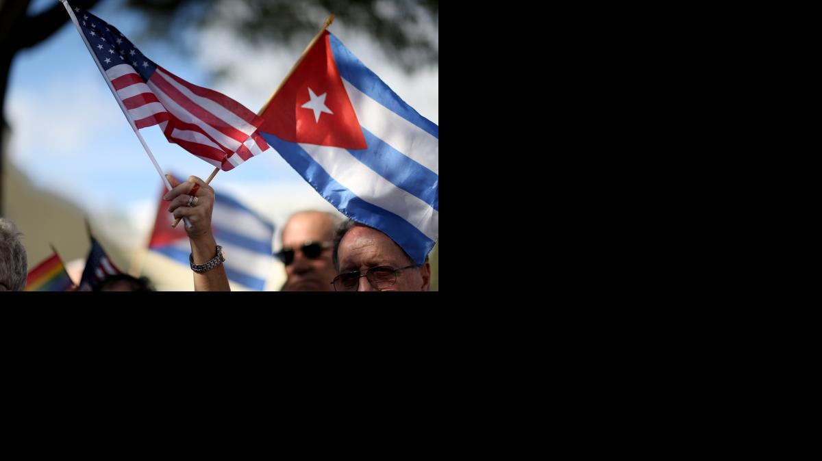
Un manifestante sostiene una bandera americana y una cubana mientras se une a otros que se oponen al anuncio del presidente estadounidense Barack Obama de un cambio en la política de Estados Unidos y Cuba en el parque José Martí el 20 de diciembre de 2014 en Miami, Florida . 