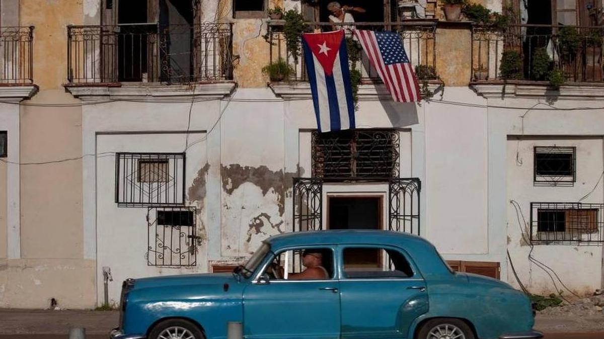 Un auto pasa junto a las banderas de Estados Unidos y Cuba en un balcón en La Habana, Cuba, el 20 de julio del 2015, el día que los dos países reanudaron sus relaciones diplomáticas.