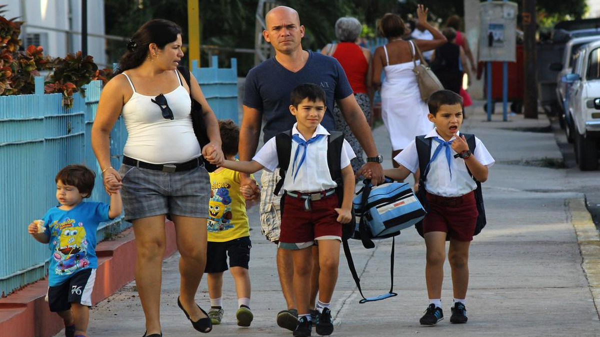 Un pareja lleva a sus hijos a la escuela en La Habana el 5 de diciembre de 2016, un día después de la inhumación de las cenizas del líder cubano Fidel Castro.