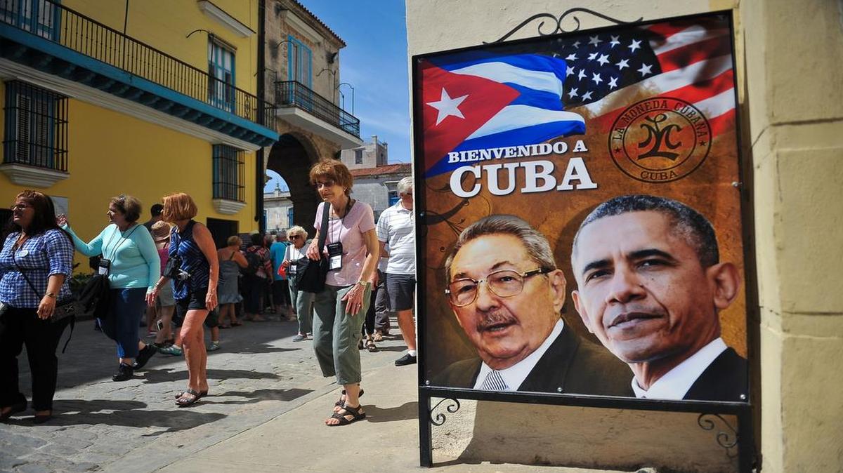 Un grupo de turistas camina junto a un póster con las imágenes de Raúl Castro y Barack Obama en La Habana.