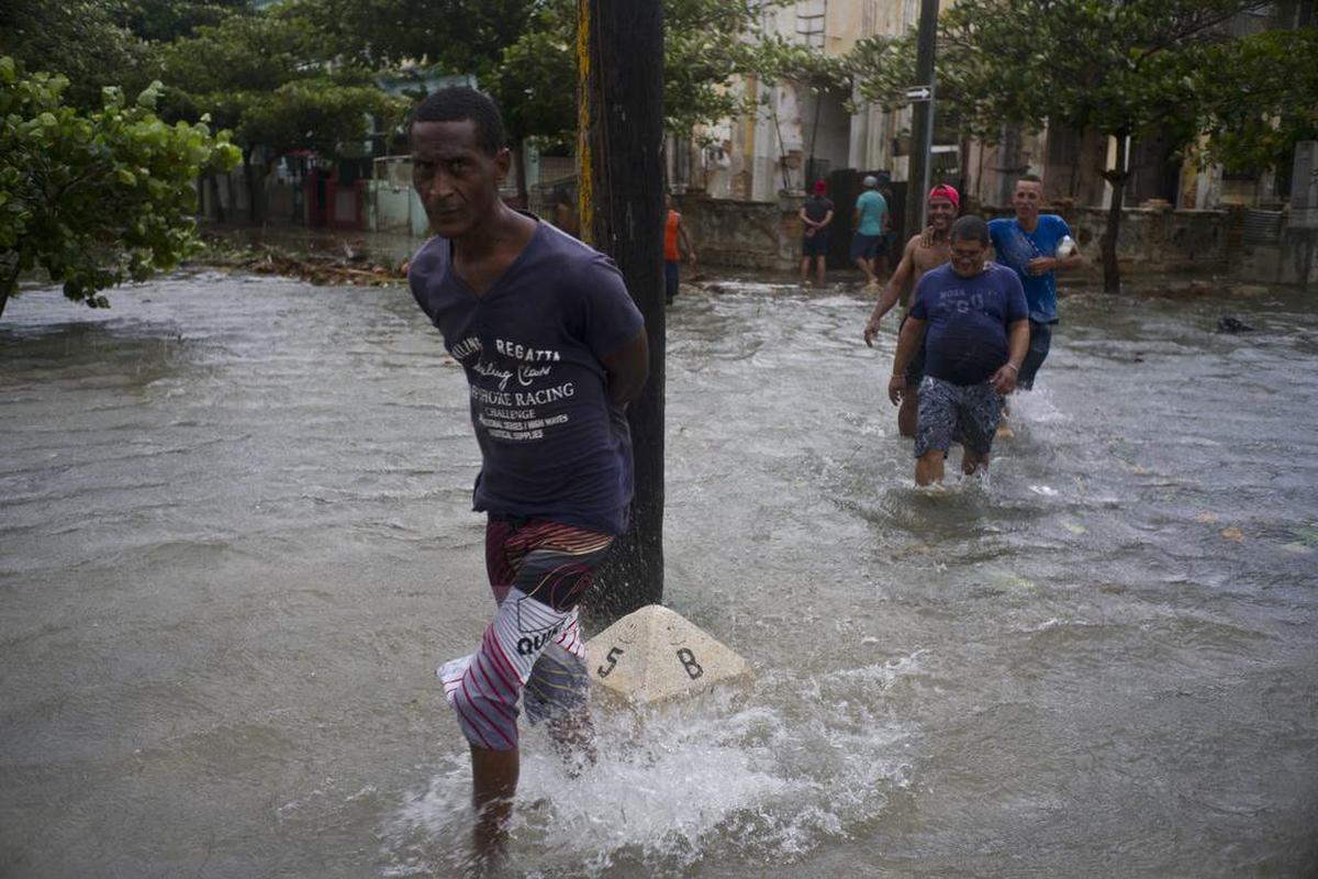 Varias personas cruzan una calle inundada en La Habana.