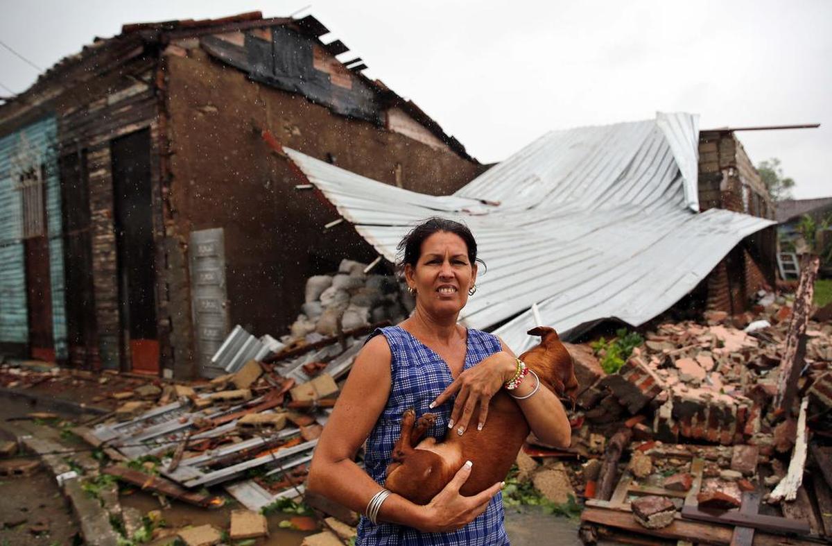 Una mujer posa con su perro frente a su casa destruida por el paso del huracán Irma, el sábado 9 de septiembre de 2017, en la ciudad central de Remedios, Cuba. Cuba sufrió el embate del huracán Irma el viernes y registró “fuertes inundaciones” en el litoral noroccidental, de Matanzas a La Habana.
