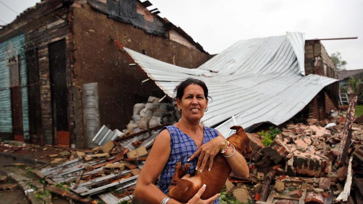 Una mujer posa con su perro frente a su casa destruida por el paso del huracán Irma, el sábado 9 de septiembre de 2017, en la ciudad central de Remedios, Cuba. Cuba sufrió el embate del huracán Irma el viernes y registró “fuertes inundaciones” en el litoral noroccidental, de Matanzas a La Habana.