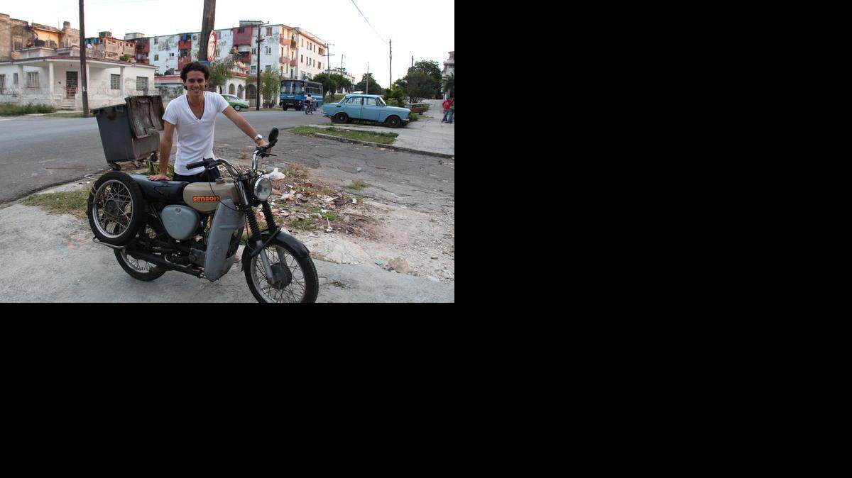 
Rainer Quintero posa junto a la moto Simson de su padre en La Habana. Roberto Quintero, que estudió en la RDA, la recibió de regalo de sus amigos alemanes a comienzos de los años 90.

