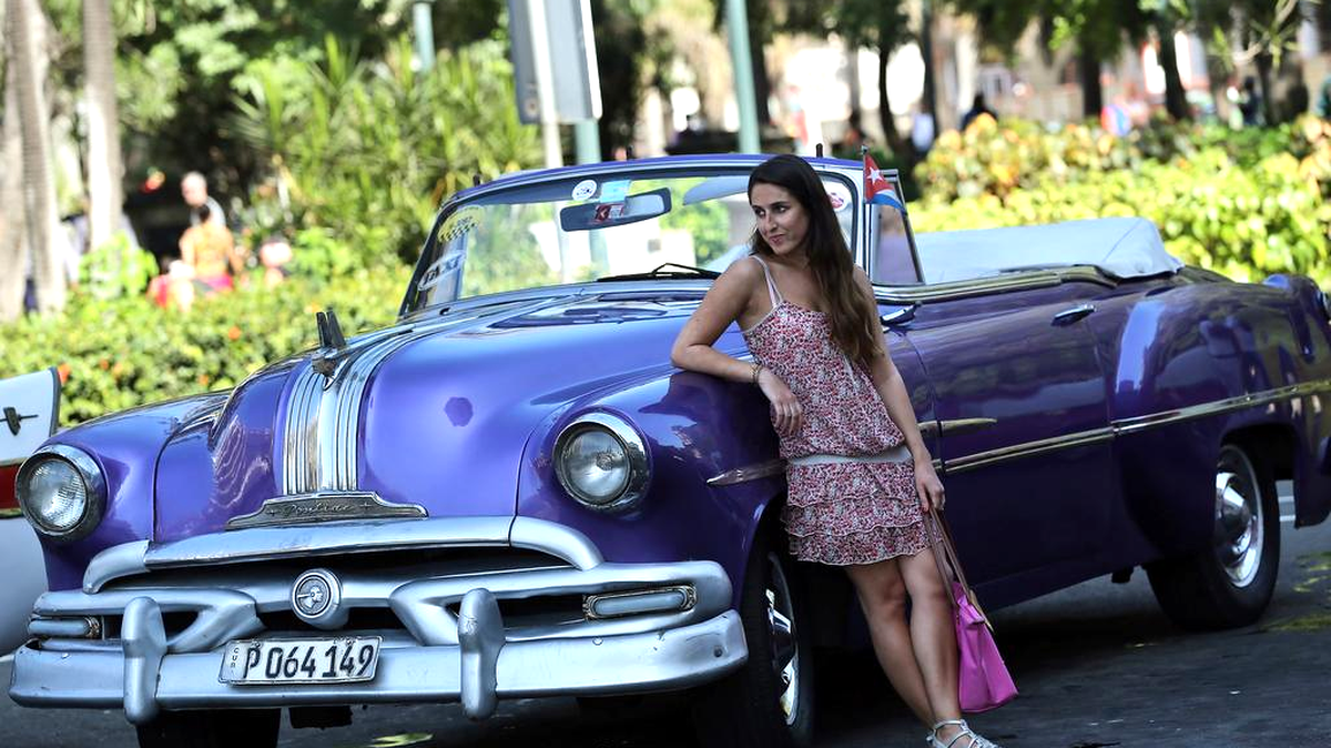 Una turista posa junto a un auto clásico este sábado, 2 de enero de 2015, en La Habana (Cuba).