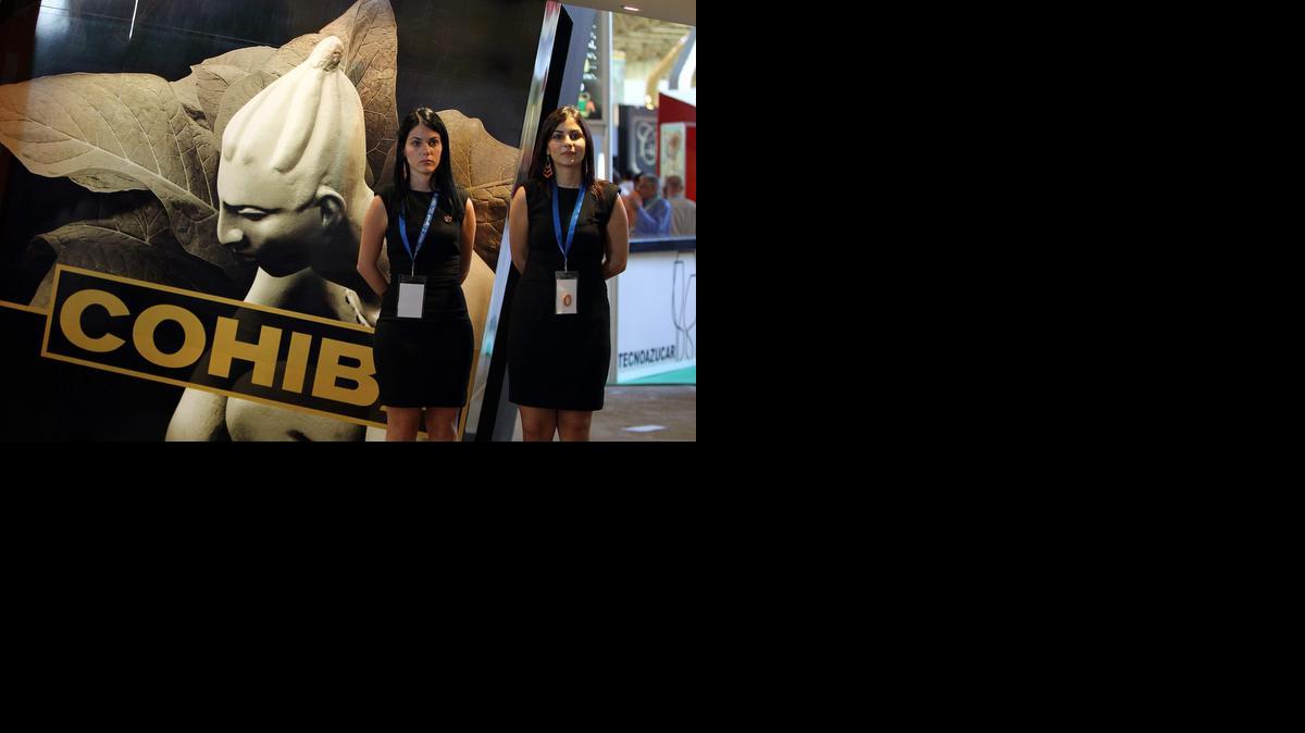 
Dos promotoras posan cerca de una publicidad de Cohíba durante la XXX Feria Internacional de La Habana, en noviembre de 2012. 
