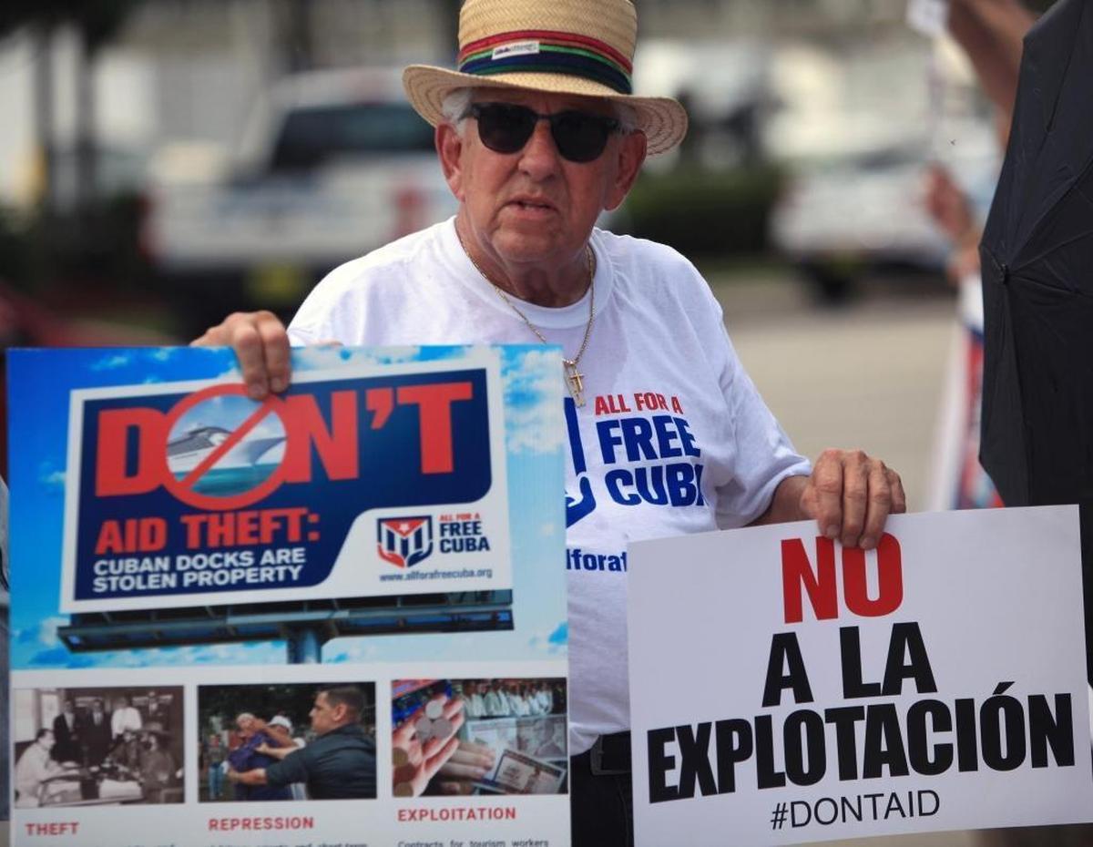 Juan Suarez, a Cuban exile, shows messages that condemn U.S.-based cruise ships that call in Cuba. Some Cuban Americans with claims on Cuban port facilities say they want to sue.