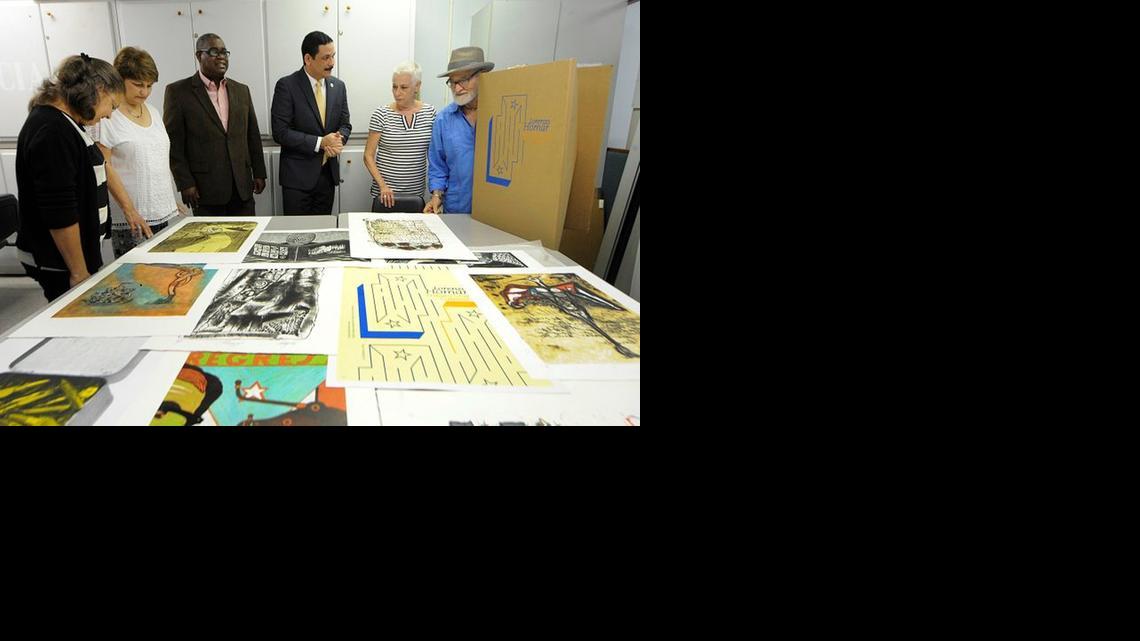 
Funcionarios y la hija del artista, Susan Homar (der.) junto al maestro Antonio Martorell (extremo derecho), observan la colección de grabados.



