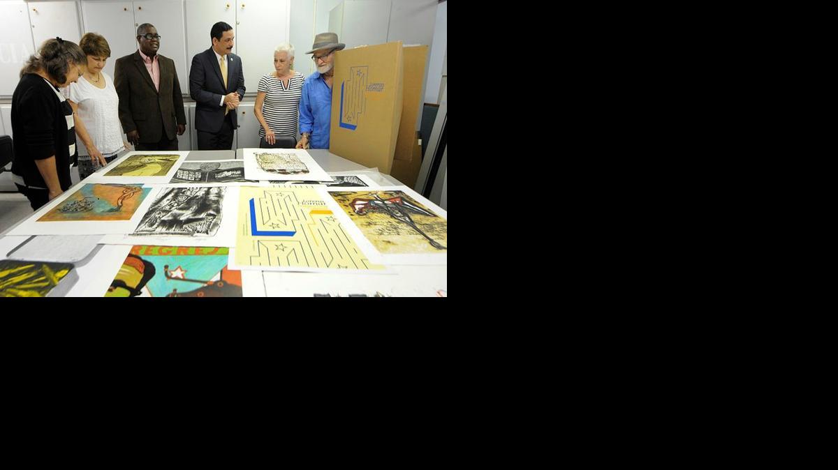
Funcionarios y la hija del artista, Susan Homar (der.) junto al maestro Antonio Martorell (extremo derecho), observan la colección de grabados.


