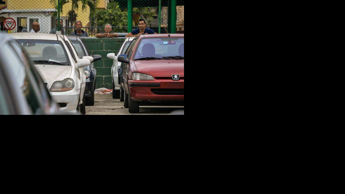 
Un grupo observa en La Habana uno de los lugares habilitados para la venta de autos de uso.



