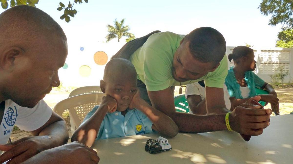 Michelot Difficile, un funcionario de protección infantil de la Organización Internacional para las Migraciones, izquierda, y Rolex Degazon, a la derecha, con Soeurs Saint Jean, intenta obtener información de un niño de seis años abandonado, que dice que su nombre es Jefferson Joseph, en una casa en Ouanaminthe, Haití. El joven fue llevado a esa casa hace seis meses después de recogerlo en un mercado local.