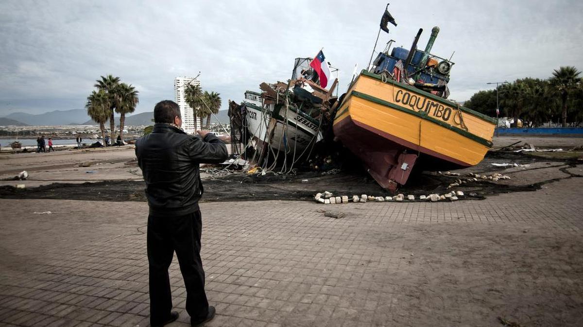 
Un hombre toma fotografías de dos barcos arrastrados a la vía Costanera por el sismo del pasado miércoles, el sábado 19 de septiembre de 2015, en la localidad costera de Coquimbo (Chile). 
