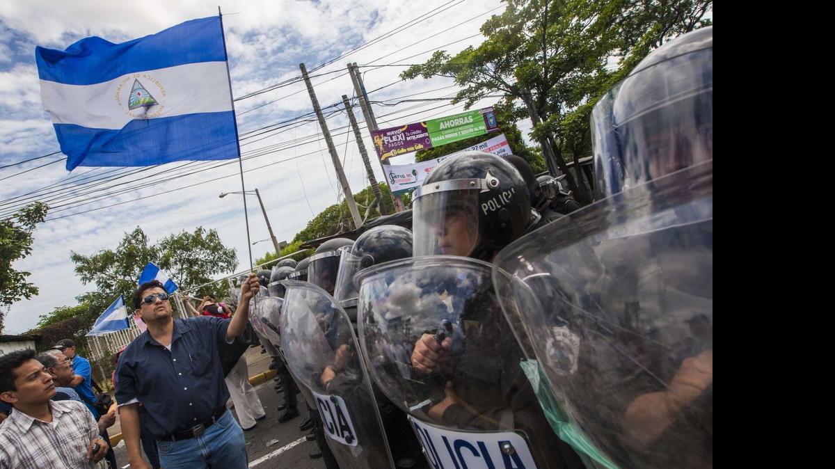
Manifestantes ondean banderas frente a agentes policiales el miércoles en Managua, durante una protesta contra el sistema electoral de Nicaragua.
