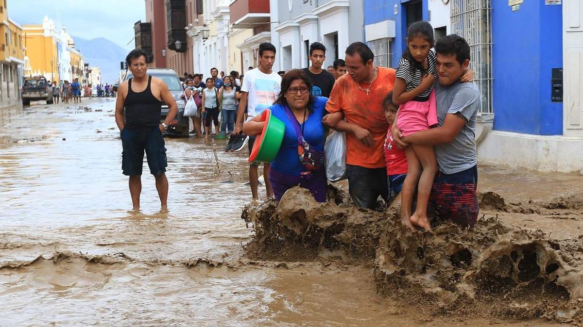 Los residentes locales intentan caminar en la ciudad de Trujillo, a 570 kilómetros al norte de Lima el 18 de marzo de 2017, trayendo barro y escombros.