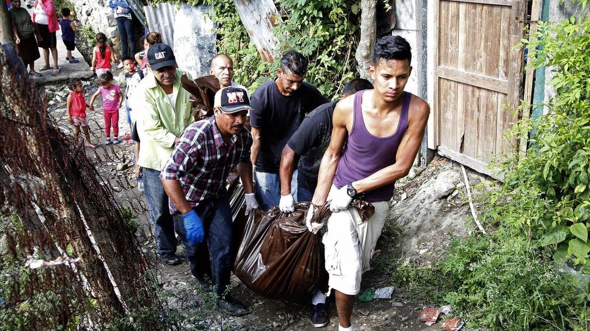 Un grupo de personas traslada un cadáver tras una masacre en un vecindario pobre en la capital hondureña el miércoles 25 de noviembre, 2015. Un hombre y cinco de sus hijos fueron asesinados este sábado, 28, a tiros por desconocidos que ingresaron por la fuerza a su vivienda en el occidente de Honduras. Esta es la tercera masacre de la semana en el país centroamericano.