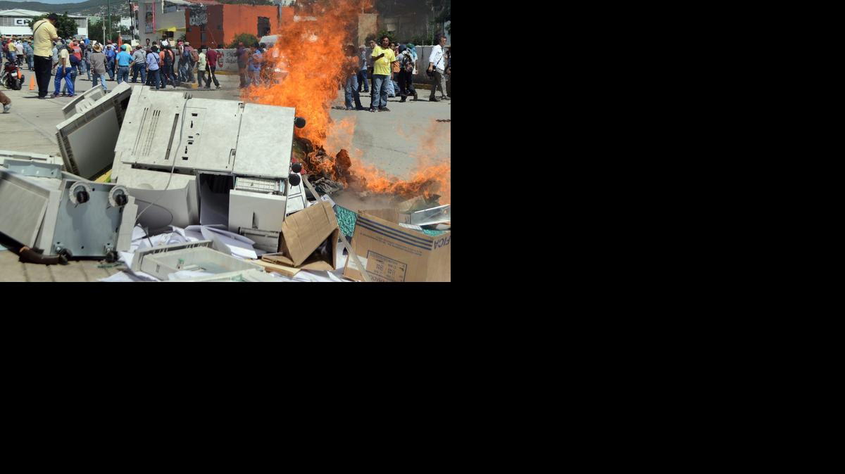 
Compañeros de los 43 estudiantes desaparecidos en Guerrero destruyen el mobiliario de una oficina encargada de programas sociales el viernes 24 de octubre de 2014, en Tixtla (México). La principal línea de investigación de la Fiscalía mexicana busca criminalizar a los 43 estudiantes desaparecidos hace cuatro semanas por supuestamente apoyar al cártel de Los Rojos, rival del grupo criminal Guerreros Unidos, denunciaron hoy familiares de los jóvenes. 
