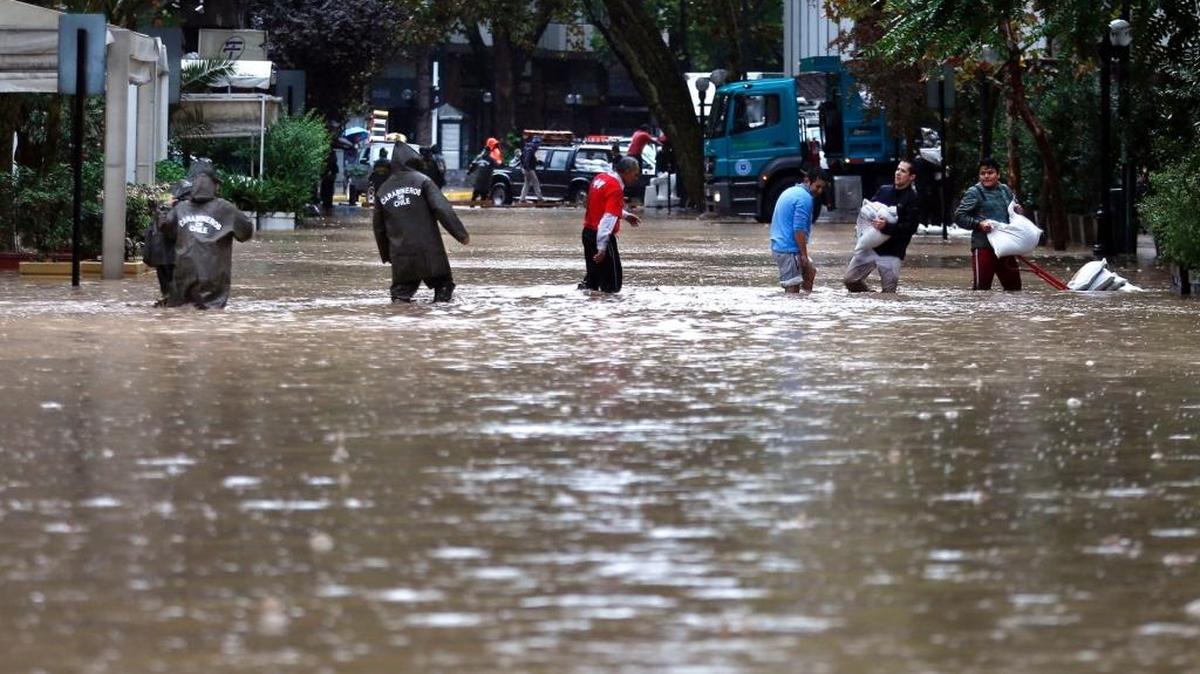 Personas son ayudadas el domingo por la policía en las calles inundadas por el río Mapocho, en Chile.