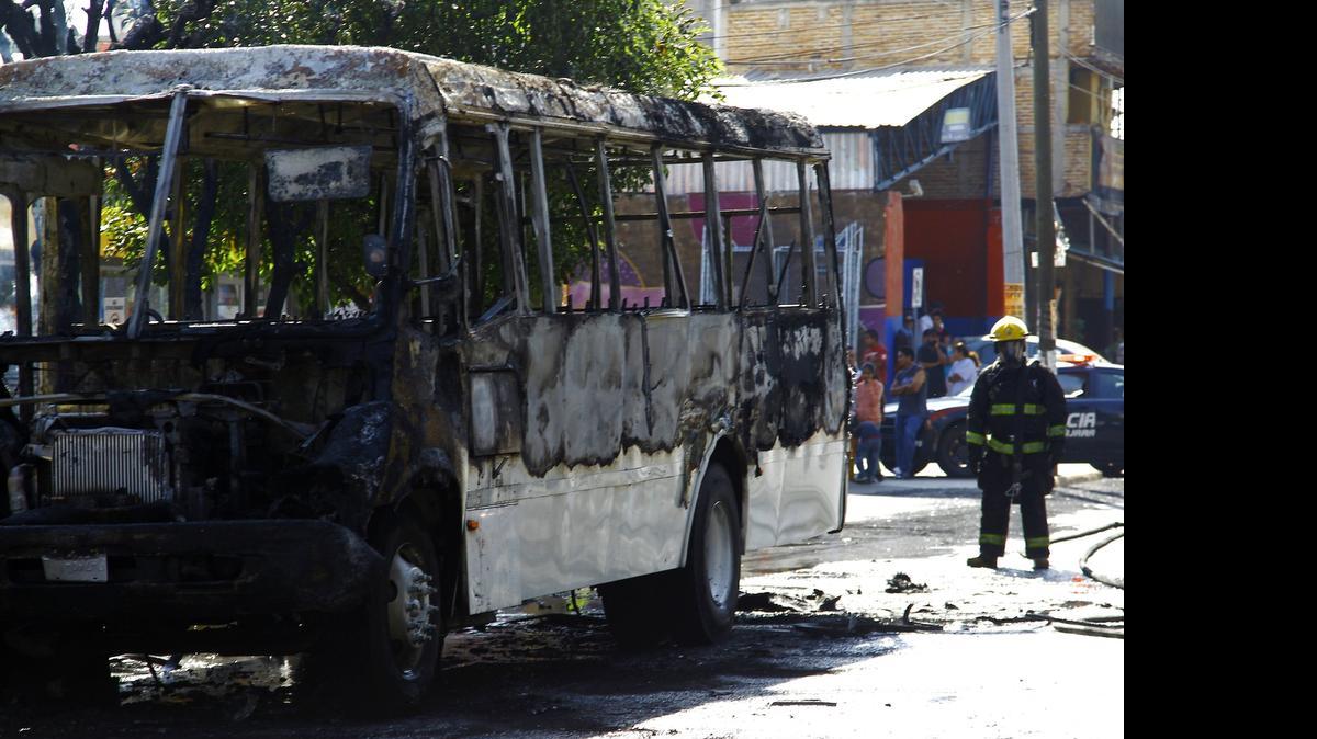 
Un bombero termina de apagar las llamas de un autobús incendiado en la ciudad de Guadalajara, México. Más de una docena de vehículos ardieron en la escalada de violencia del viernes.
