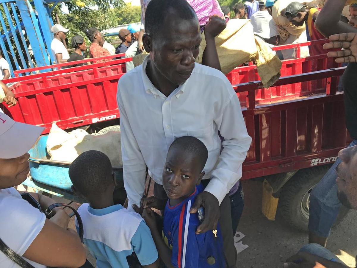 Dos niños que son llevados ilegalmente a la República Dominicana se aferran a su padre mientras los trabajadores de protección infantil de la Organización Internacional para las Migraciones (OIM) y el Instituto de Bienestar Social e Investigaciones de Haití (IBESR) les hacen preguntas.