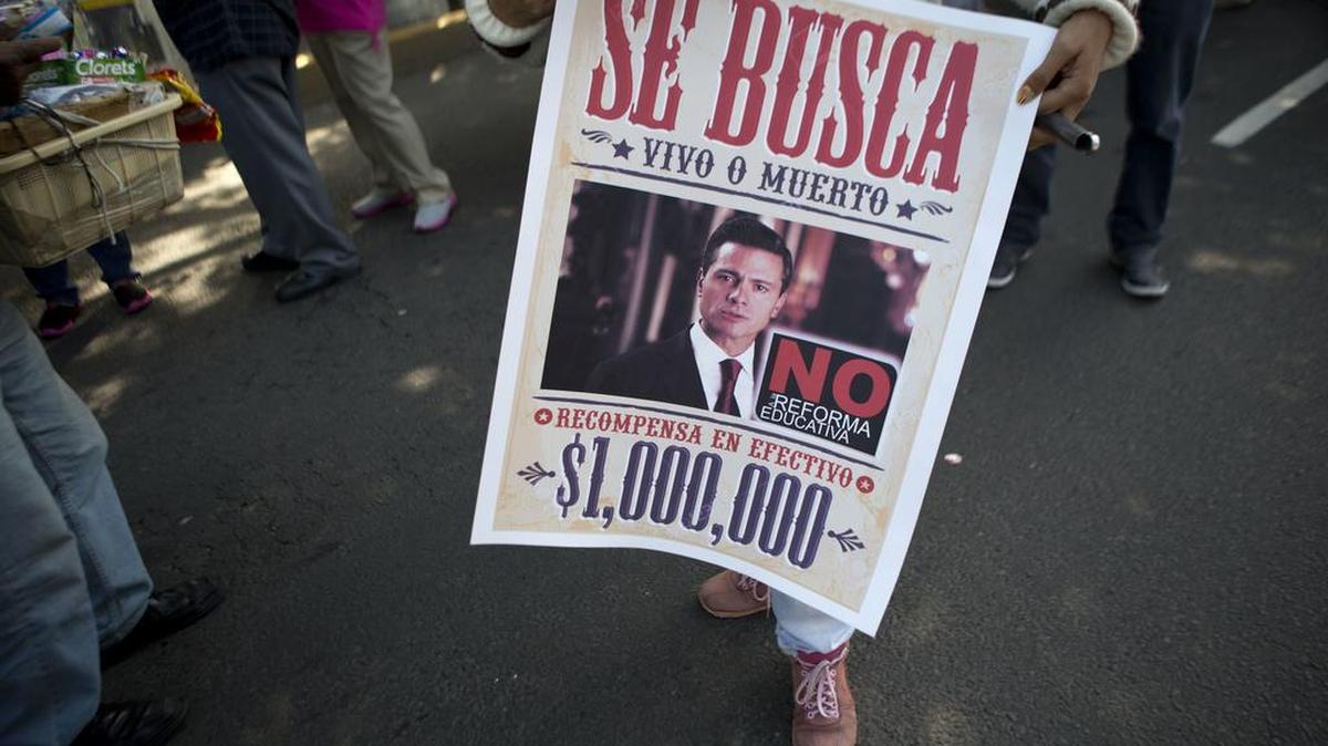 Un manifestante sostiene un poster con la foto del presidente mexicano Enrique Peña Nieto com delincuente buscado.