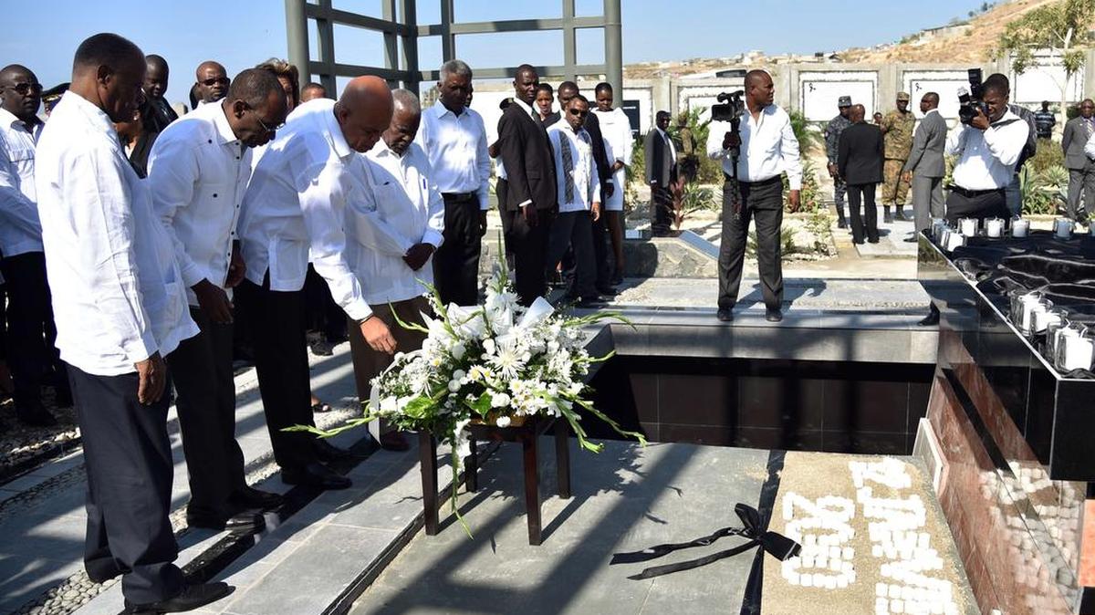 El presidente de Haití, Michel Martelly(2 der.) y el primer ministro, Evans Paul (2 izq.), colocan el martes flores en honor a las víctimas durante una ceremonia en Puerto Príncipe.