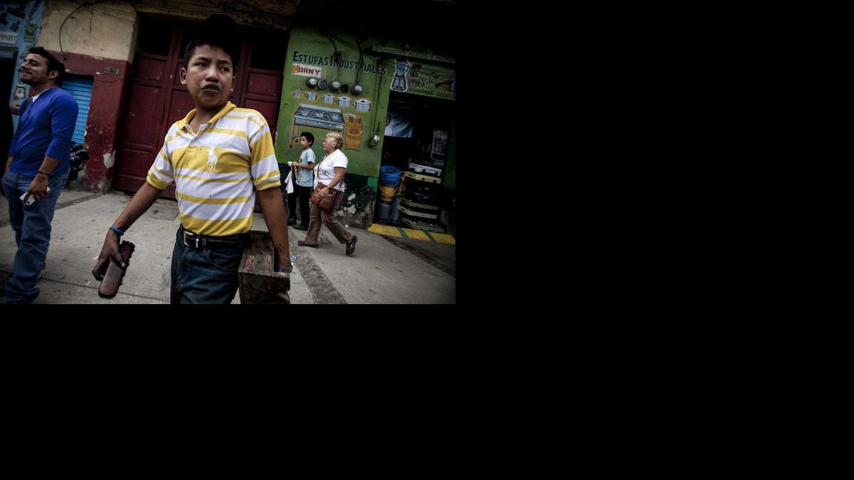 
Un niño, lustrador de zapatos, pasa frente a un inmueble donde la Procuraduría General de la Nación rescató en la Ciudad de Guatemala a 55 menores y capturó a dos hombres que supuestamente los obligaba a trabajar en la calle y a pedir limosna en la capital guatemalteca. 
