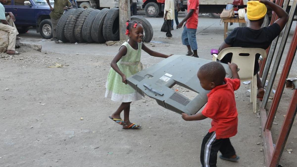 Un par de niños juegan con un pedazo de televisor afuera del museo del escultor Andre Eugenes en Puerto Prícipe, en abril.