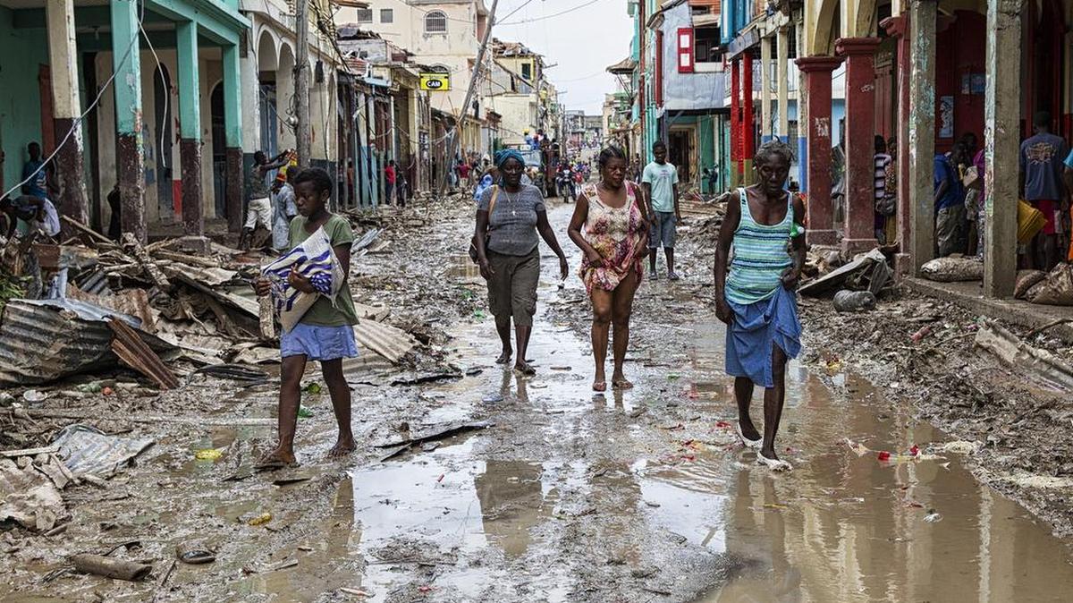 Varias personas caminan por una calle inundada tras el impacto del huracán Matthew, el jueves 6 de octubre de 2016 en el poblado de Jeremie, Haití. La foto fue tomada por la Misión de la ONU en Haití (MINUSTAH).